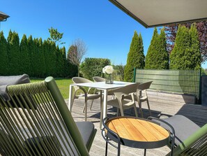 An outdoor patio with a table and chairs, surrounded by greenery and a fence. - Premium apartment WIESENZEIT, 2 entrances, 2 terraces & plenty of space to breathe deeply (Seekirchen am Wallersee)