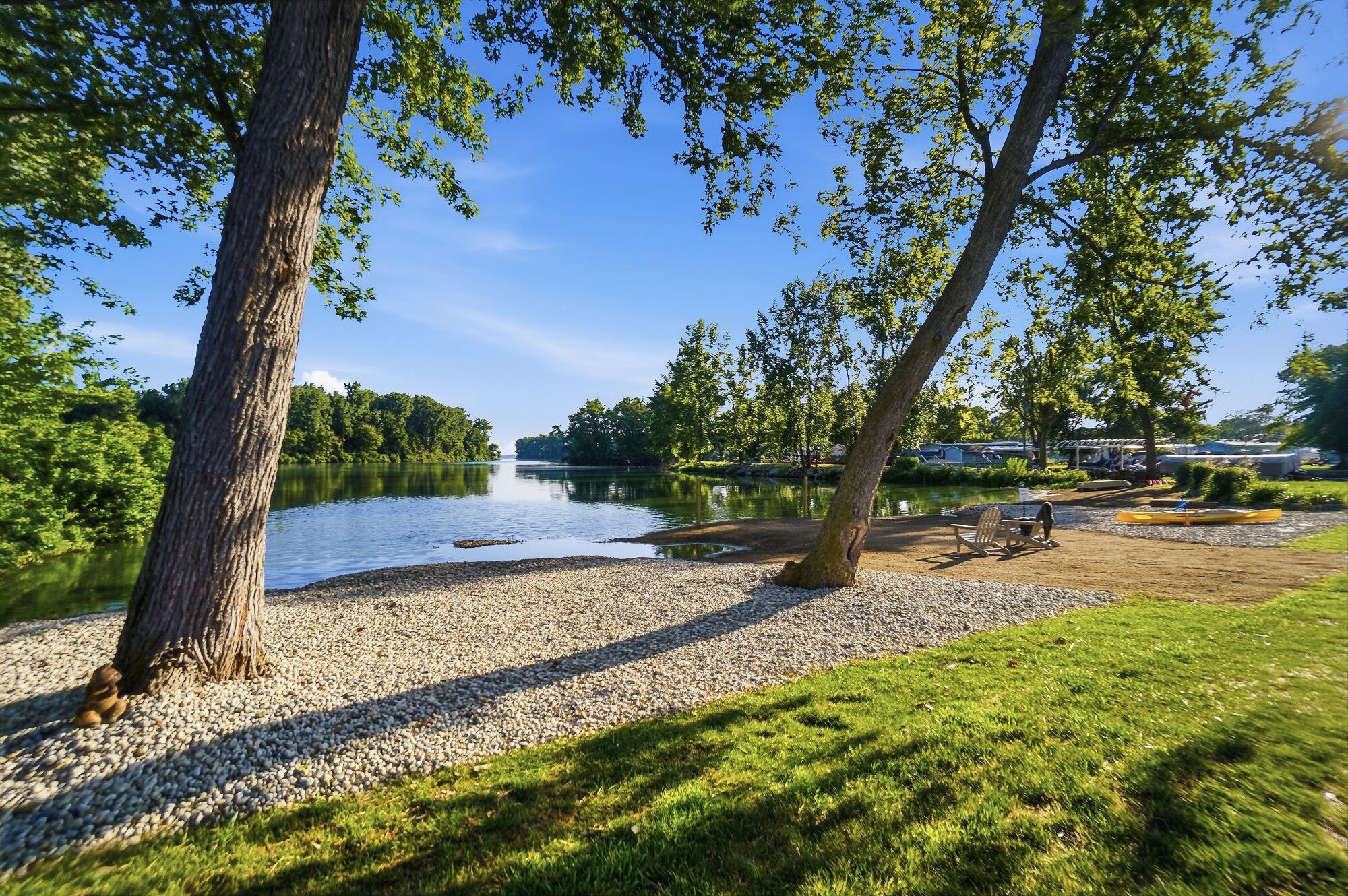 Ein Park am Seeufer mit Kiesweg, Bäumen und freiem Blick auf den See.