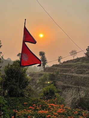 A flag with a red background and a white maple leaf, set against a sunset. - Peaceful, Charming- bedroom bed & breakfast in lovely Dhulikhel #4 (Dhulikhel)