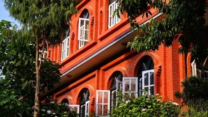 A red brick building with arched windows and a balcony. - Peaceful, Charming- bedroom bed & breakfast in lovely Dhulikhel #4 (Dhulikhel)