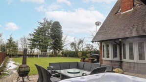 Un espace patio aménagé avec un jacuzzi, du mobilier d’extérieur et un barbecue.