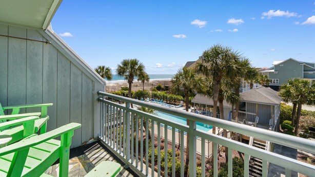 Ein Balkon mit Blick auf einen Pool, Palmen und einen Strand.