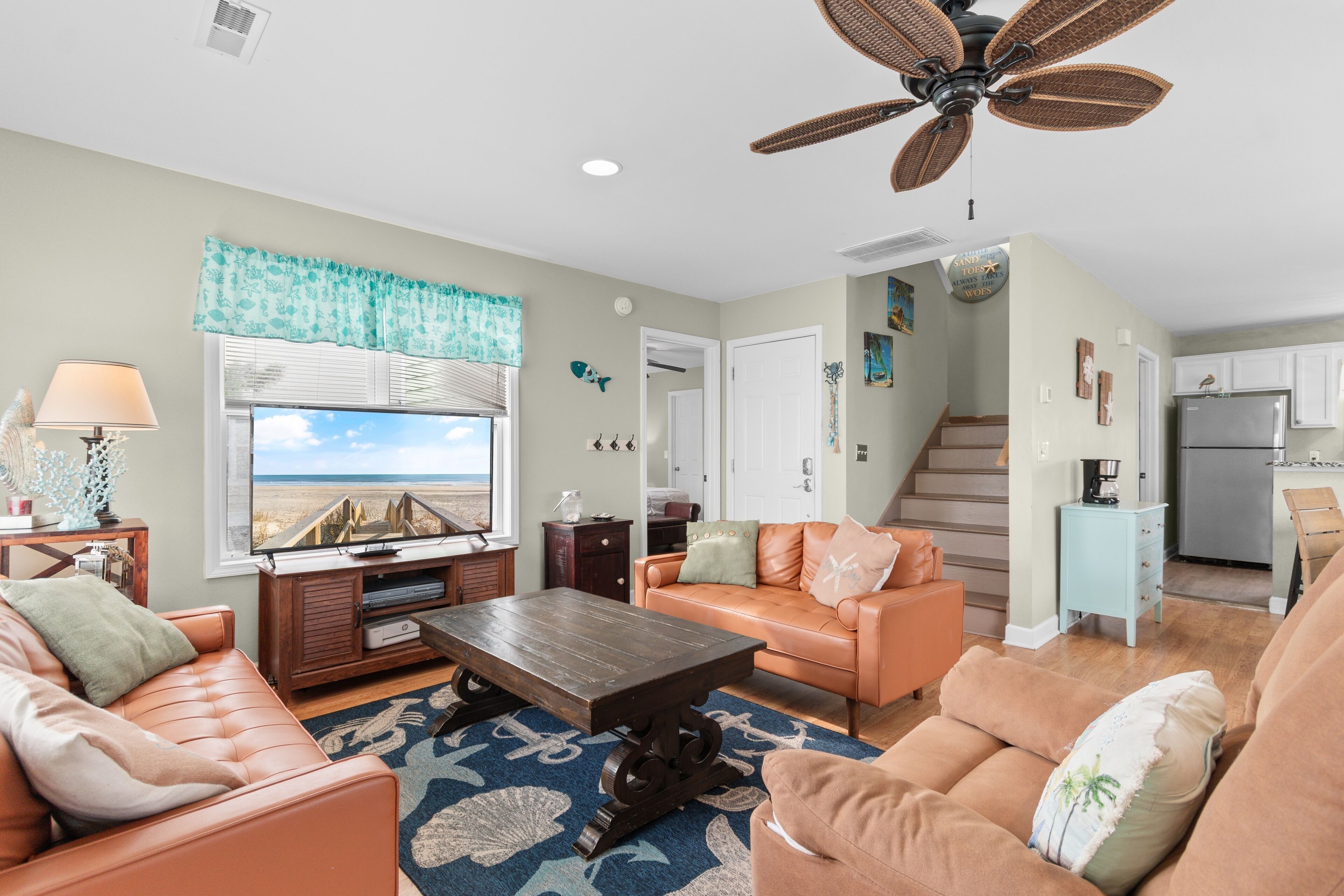 A living room with a television, sofa, coffee table, and a ceiling fan.