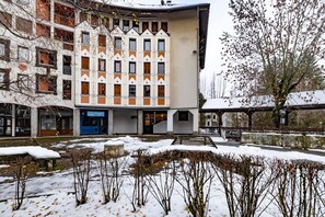 Un edificio de varios pisos con un patio central, un corredor cubierto y un terreno cubierto de nieve.