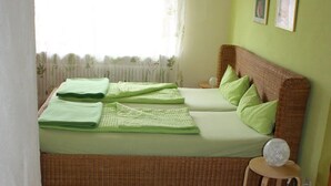 A single bed with green bedding, a small bedside table with a lamp, and a green and white striped rug. - Apartment '1' with Balcony and Wi-Fi (Herbolzheim)