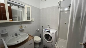 Une petite salle de bain comprenant un lavabo, des toilettes et un lave-linge.