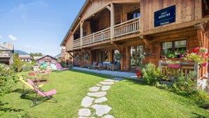A wooden chalet with a balcony, a sign reading "SIMPLY MORZINE Chalet Central", and outdoor seating with flowers. - Simply Morzine - Chalet Central (Morzine)