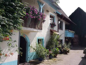 A traditional building with a balcony, potted plants, and a garden area. - Apartment '2' with Balcony and Wi-Fi (Herbolzheim)