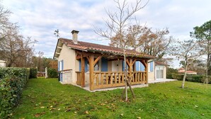 Ein Haus mit einer Holzterrasse, einem umzäunten Garten und blauem Himmel.
