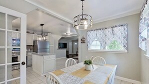 Uma cozinha moderna com armários brancos, forno embutido e uma área de refeições com mesa e cadeiras de madeira.