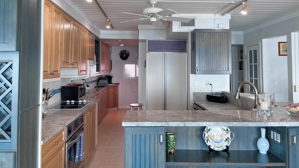 Een moderne keuken met houten kasten, een centraal eiland en een geïntegreerde koelkast.