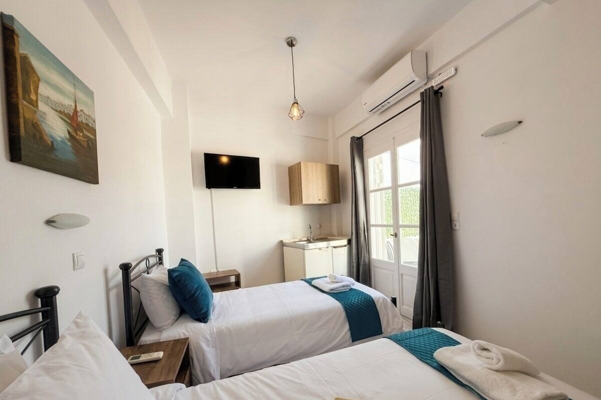 Ein Hotelzimmer mit zwei Betten, einem Fernseher, einer Klimaanlage und einem Bild an der Wand.