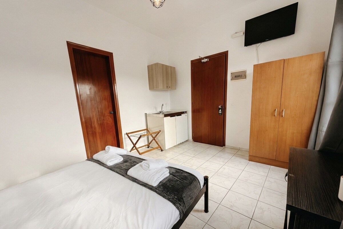 Une chambre d’hôtel équipée d’un lit, d’un bureau, d’une télévision et d’armoires.