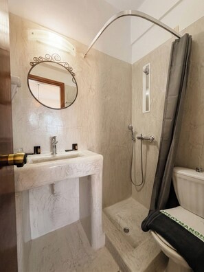 A bathroom with a marble sink, a shower, and a toilet. - Aegean Nest Beach Studios - Adults Only (Santorini)