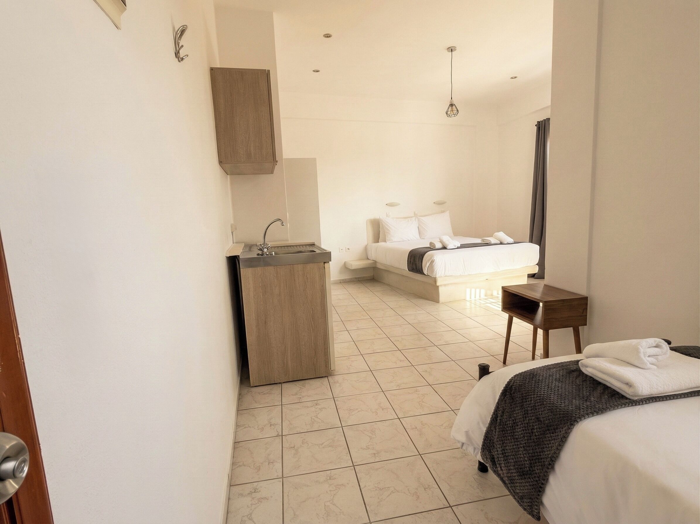 A modern hotel room with a bed, bedside table, and a built-in sink.
