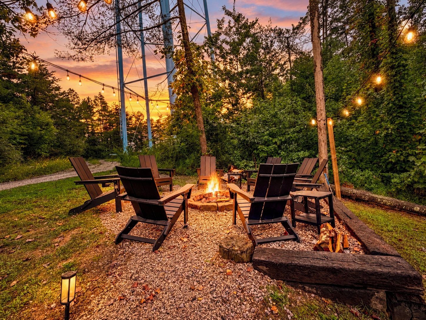 An outdoor seating area with chairs around a fire pit, surrounded by trees and a clear sky.