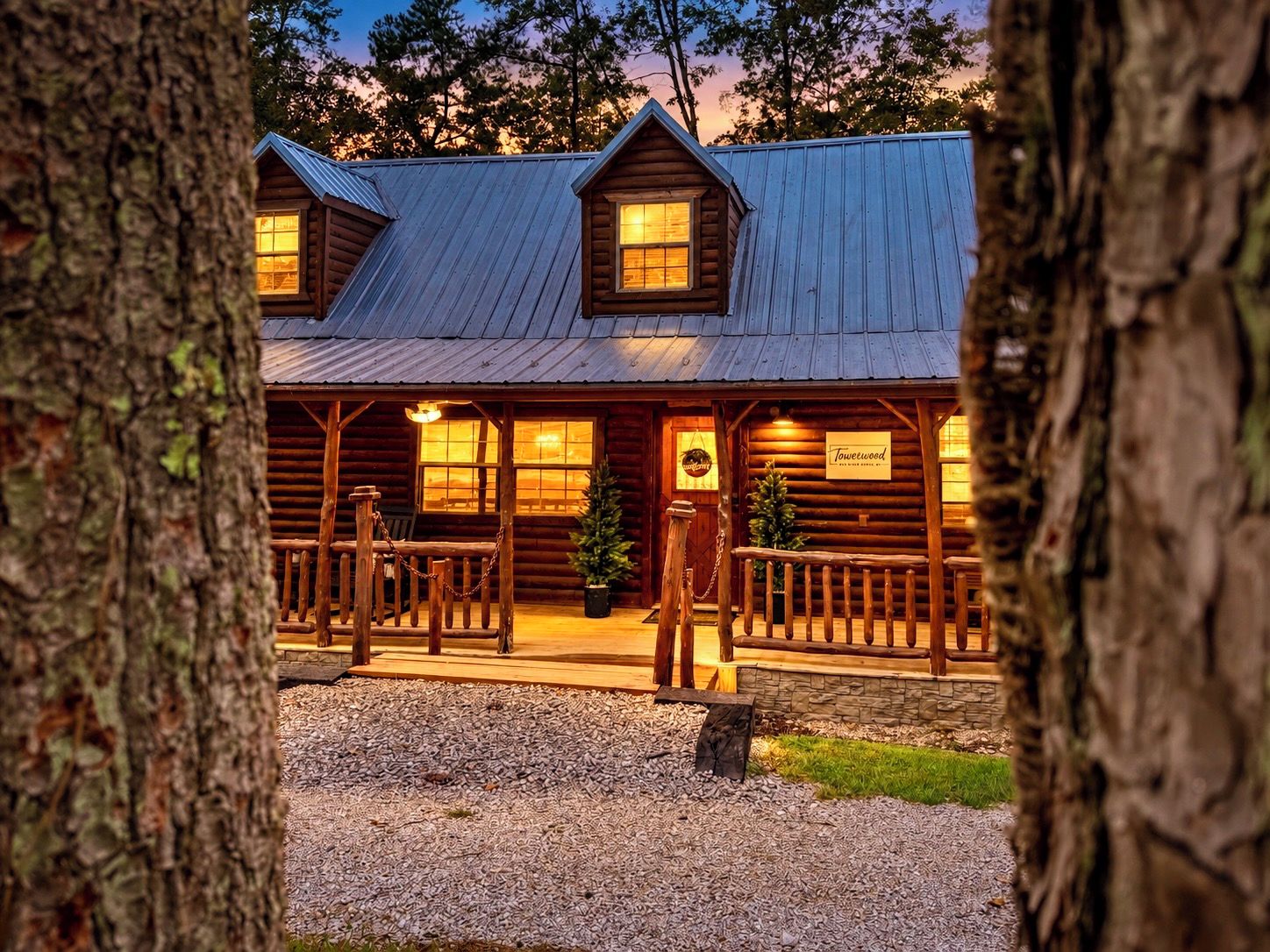 A log cabin with a porch, a Christmas tree, and a sign that reads 'Towerwood.'