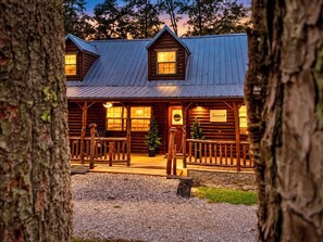 Une cabane en rondins avec un porche, un sapin de Noël et une enseigne sur laquelle on peut lire « Towerwood ».