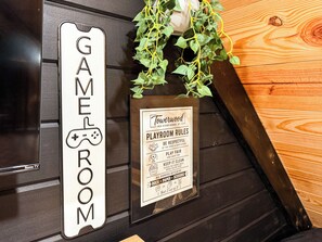 Un mur avec une pancarte indiquant « SALLE DE JEUX » et une autre pancarte intitulée « Règles de la salle de jeux », qui comprend des directives concernant le comportement à adopter et les règles de savoir-vivre à respecter pendant les jeux.