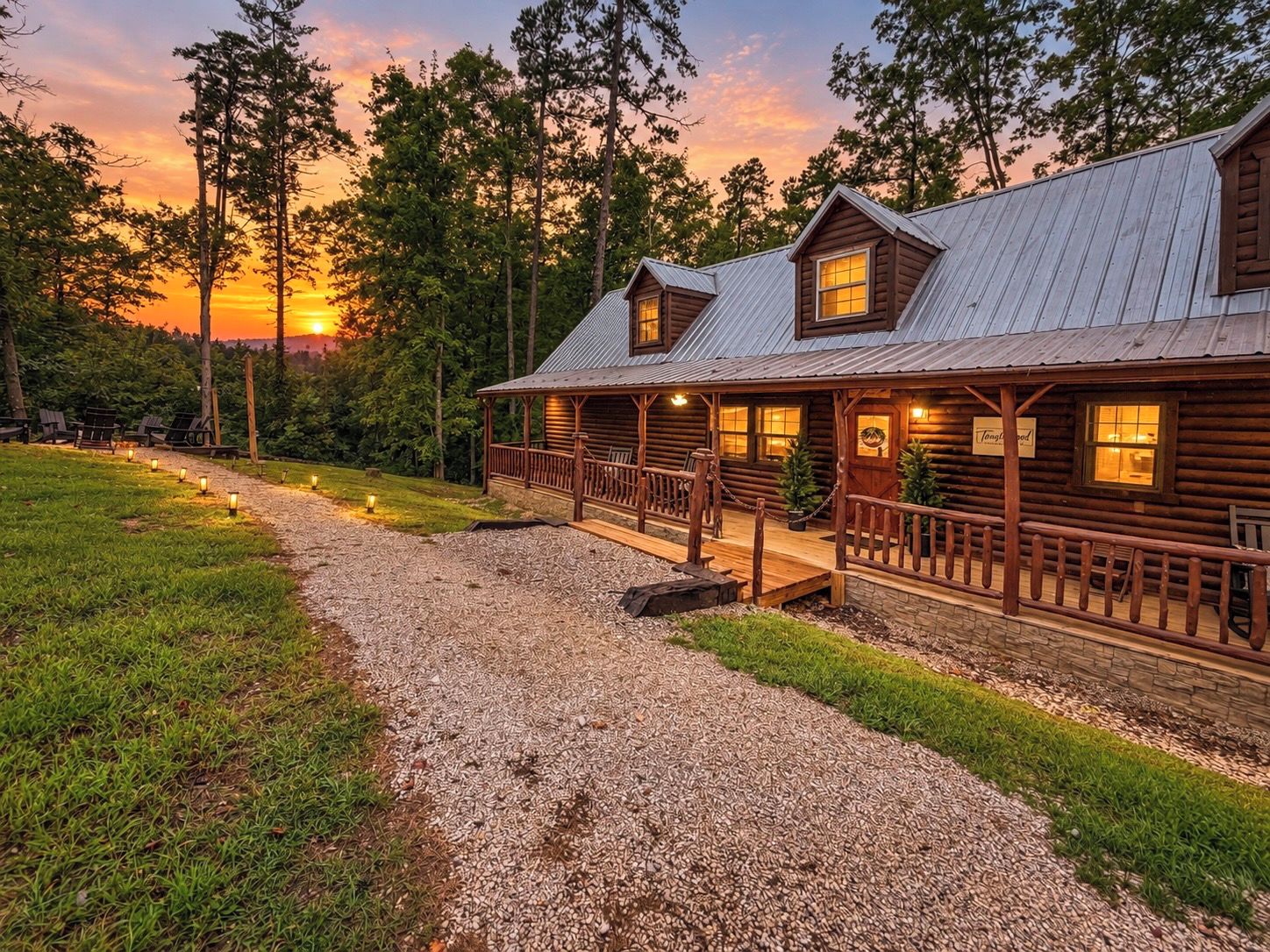 A log cabin with a porch and a gravel driveway.
