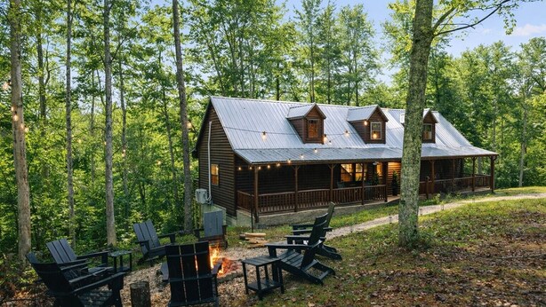 A cabin with a porch, surrounded by trees, and equipped with outdoor seating and a fire pit. - RRG Cabin l Treetop Deck•HotTub•Firepit•Putting•OutdoorTV•Sleeps8•Pets (Campton)
