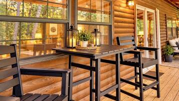 A wooden deck with a table and chairs, large windows, and a lantern with candles.