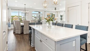 A modern kitchen with a large island, grey cabinetry, and a view of the outdoors. - Seacrest "Isle Be Back" 3BR Condo, Overlooking Pool, Steps to beach! (Inlet Beach)