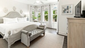A bedroom with a large bed, a bench, a ceiling fan, and a view of the outdoors. - Seacrest "Isle Be Back" 3BR Condo, Overlooking Pool, Steps to beach! (Inlet Beach)