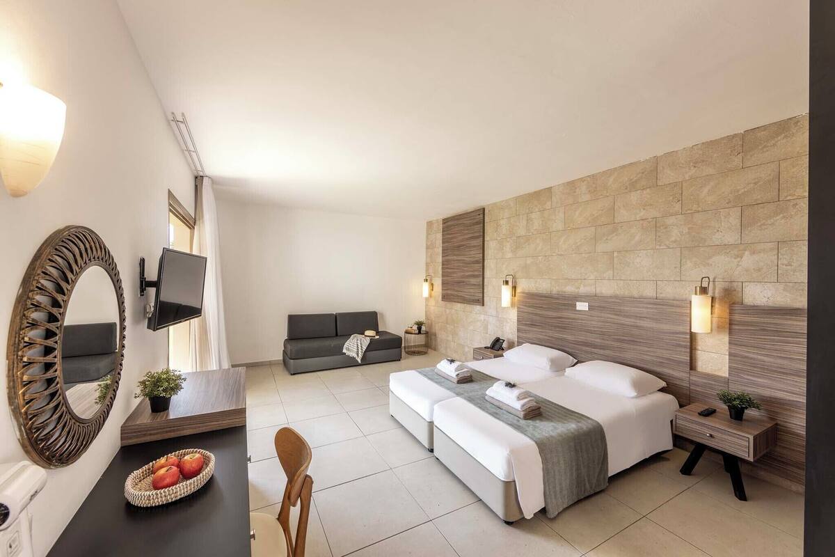 Een moderne hotelkamer met een groot bed, een bank, een televisie en een tv aan de muur.