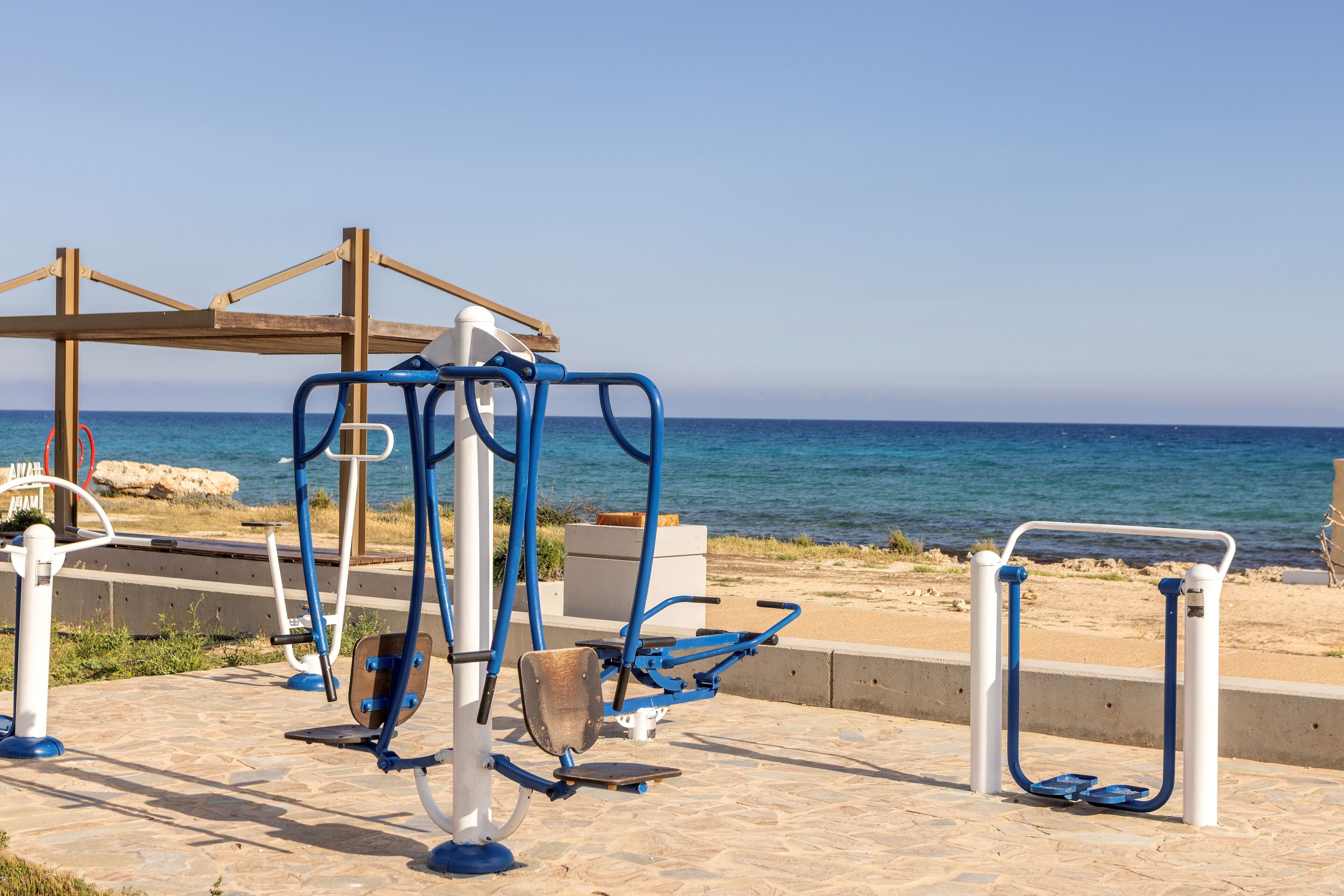 Outdoor exercise equipment near a beach with a clear view of the sea.