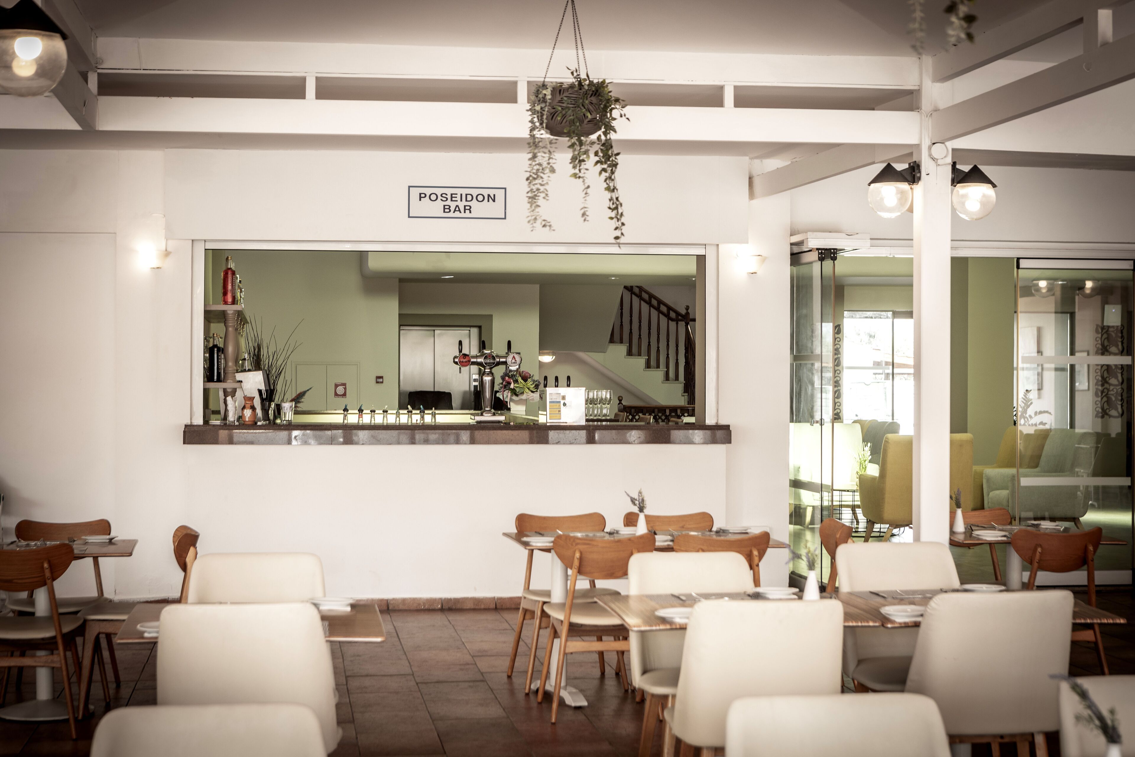 A restaurant interior with tables and chairs, a bar counter, and a staircase.