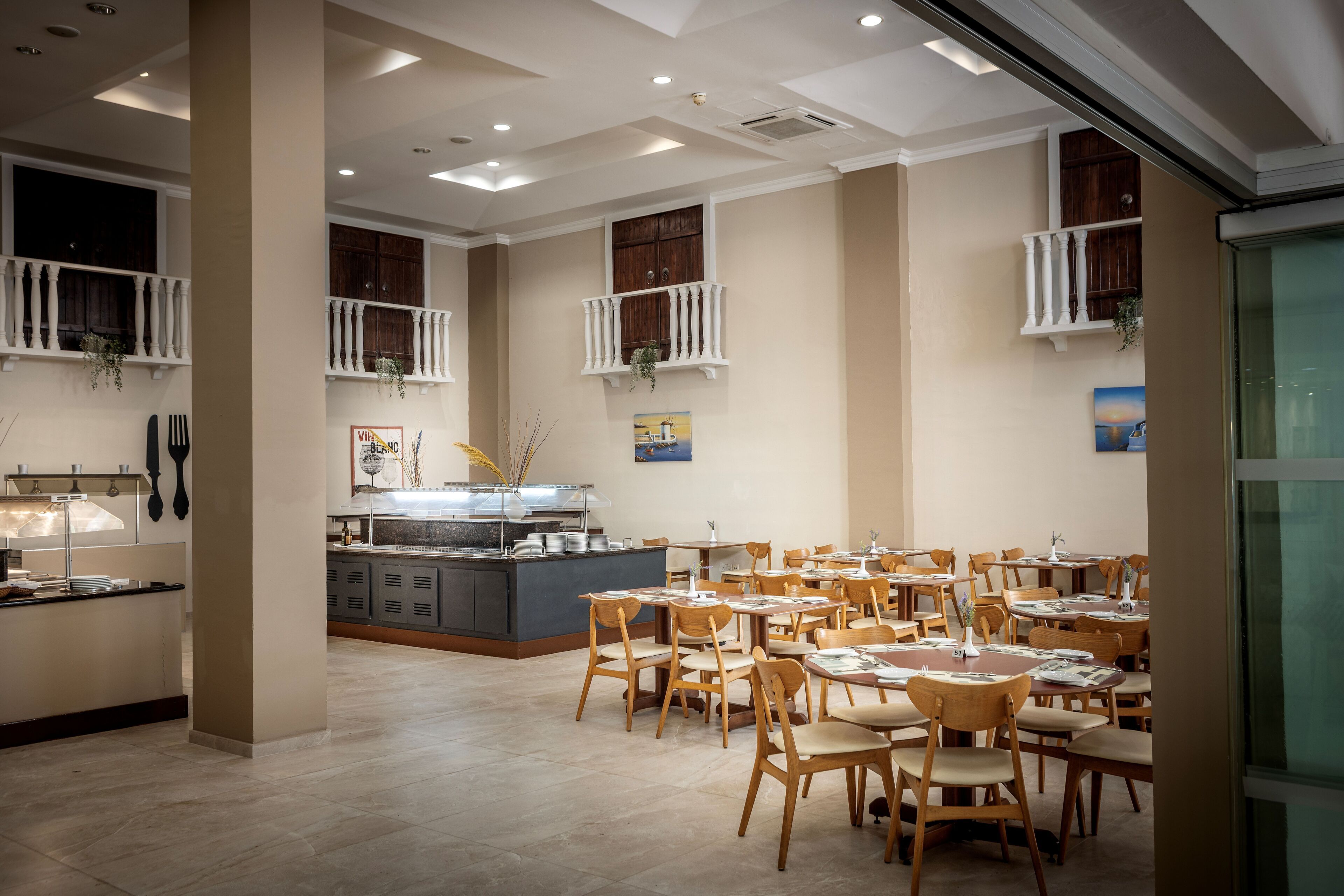Comedor con varias mesas y sillas, un mostrador de buffet y vistas al exterior.