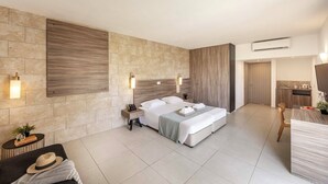 Une chambre d’hôtel moderne équipée d’un grand lit, d’un bureau, d’une chaise, d’une petite table et d’un climatiseur fixé au mur.