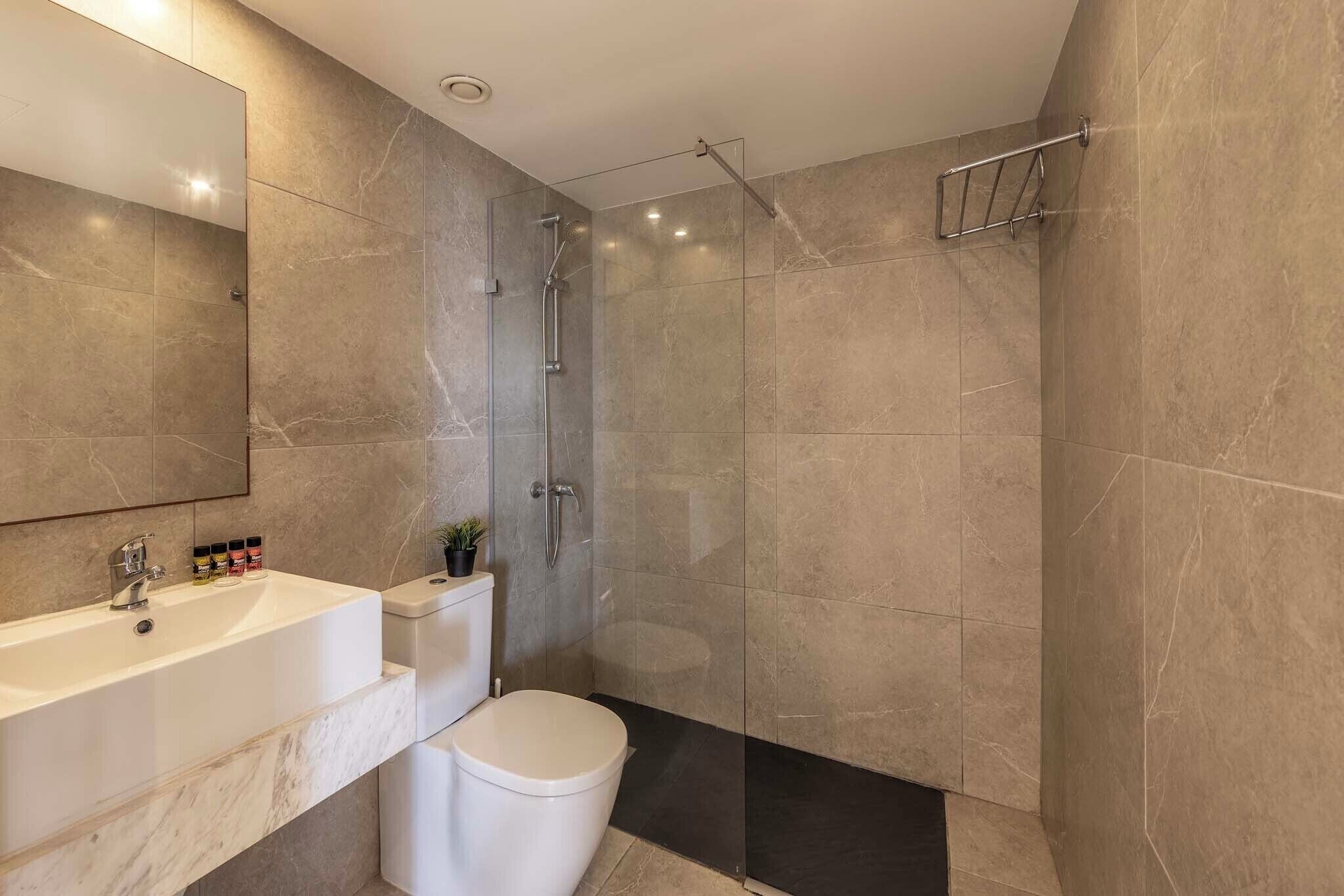 A modern bathroom with a shower, toilet, and sink.
