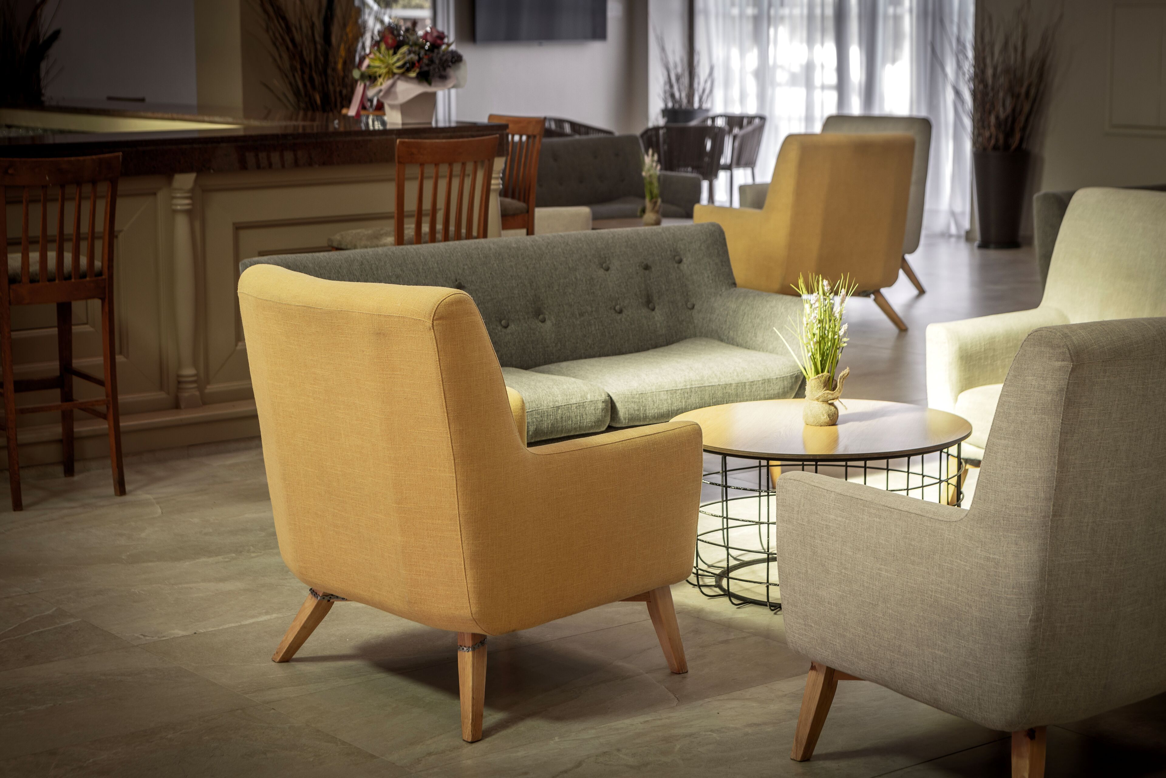 Una sala moderna con un sofá, sillones, una mesa de centro y un comedor con sillas.