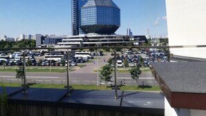 A view of a parking lot with multiple cars and a large building with a unique dome-shaped top in the background. - Stylish Apartment with a Terrace (Minsk)