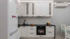 A modern kitchen with white cabinets, a black countertop, and a built-in dishwasher. - Stylish Apartment with a Terrace (Minsk)