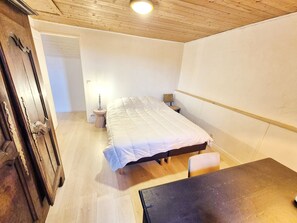 A bedroom with a bed, bedside tables, a chair, and a wooden floor.
