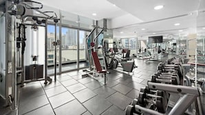 A modern gym with various exercise equipment, large windows, and a city view. - Urban Chic 1Bedroom in DEC Tower Marina (Dubai)