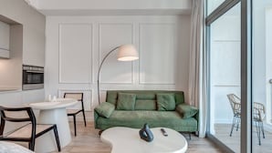 A modern living room with a green sofa, a white coffee table, and a floor lamp. - Urban Chic 1Bedroom in DEC Tower Marina (Dubai)
