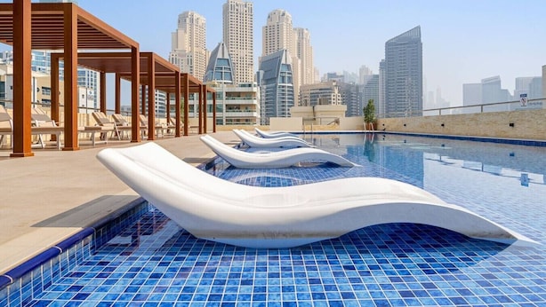 A rooftop pool with lounge chairs and a city skyline in the background. - Urban Chic 1Bedroom in DEC Tower Marina (Dubai)