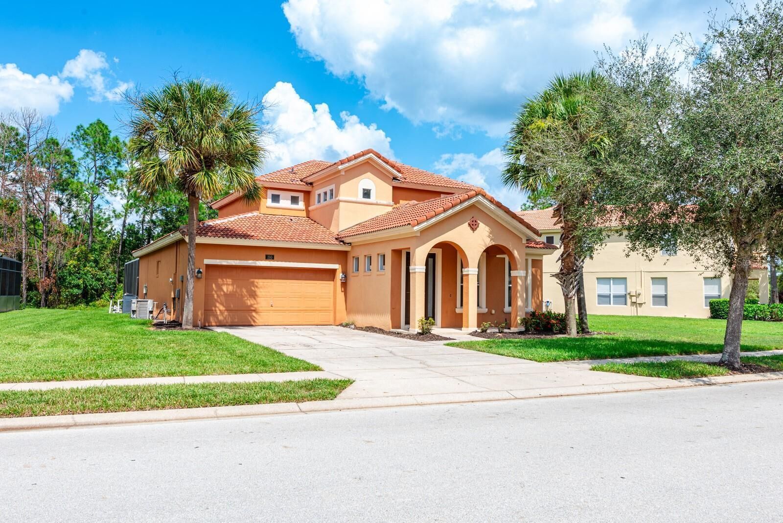 A two-story house with a red-tiled roof, a garage, and a well-maintained lawn.