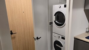 Un lavadero pequeño con dos lavadoras apiladas, una puerta de madera y una pequeña encimera.