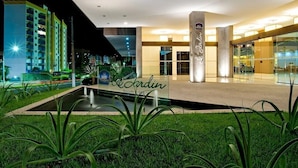 A hotel entrance with a pool, greenery, and a sign reading "Le Jardin Resorts & SPA". - Apartamento Le Jardin  (Caldas Novas)