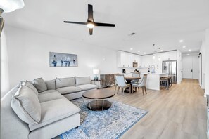 A modern living room with a sofa, a round coffee table, and a dining area with chairs and a table.