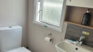 Een kleine badkamer met toilet, wastafel en raam.