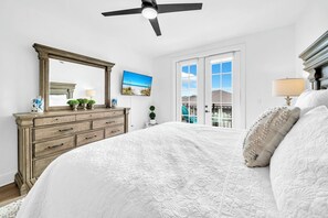 A bedroom with a large bed, a dresser, a ceiling fan, a window with a view, and a painting on the wall. - The Grove Juniper 223 - 2 Bedrooms - Lazy River - Seascape Resort (Miramar Beach)