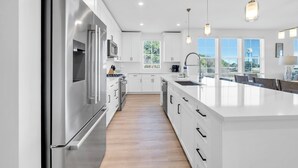 A modern kitchen with stainless steel appliances, white cabinetry, and a large island with a sink. - The Grove Dogwood 331 - 4 Bedrooms - Lazy River - Seascape Resort (Miramar Beach)