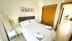 A hotel room with a bed, nightstands, a lamp, a painting, a wardrobe, and a chair. - Penthouse, 2-bedroom apartment with pool views (Sucina)