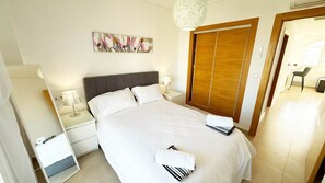 A hotel room with a bed, nightstands, a lamp, a painting, a wardrobe, and a chair. - Penthouse, 2-bedroom apartment with pool views (Sucina)